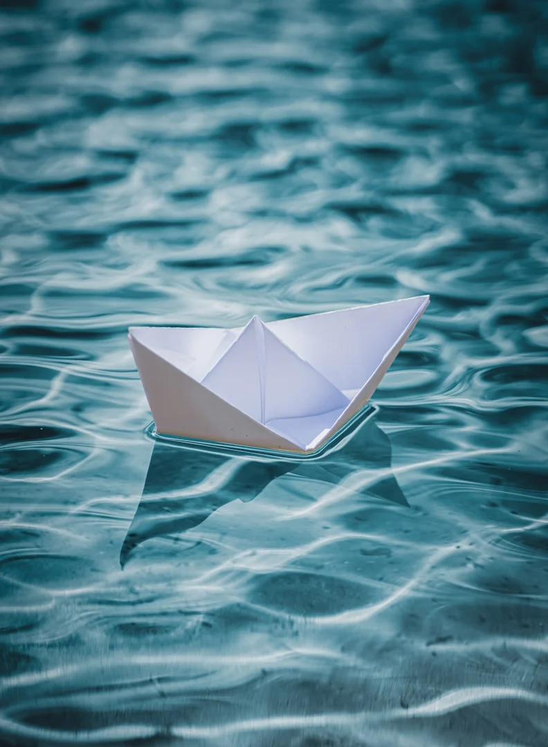 Ein Papierboot treibt auf ruhigem Wasser